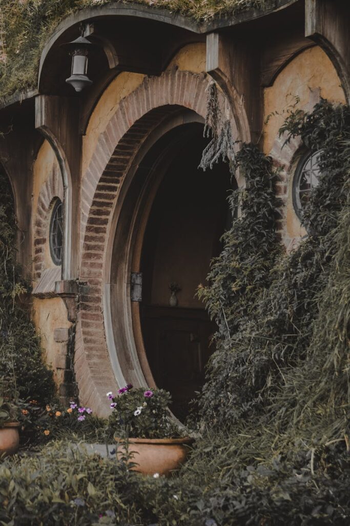 Round wooden door surrounded by vibrant greenery, echoing hobbit house design.